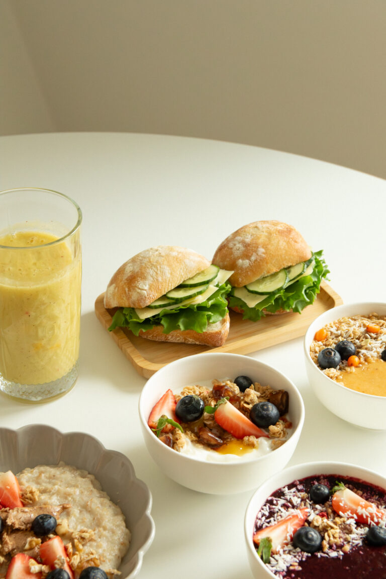 Täytetyt sämpylät, smoothie ja aamiaiskulhot pöydällä